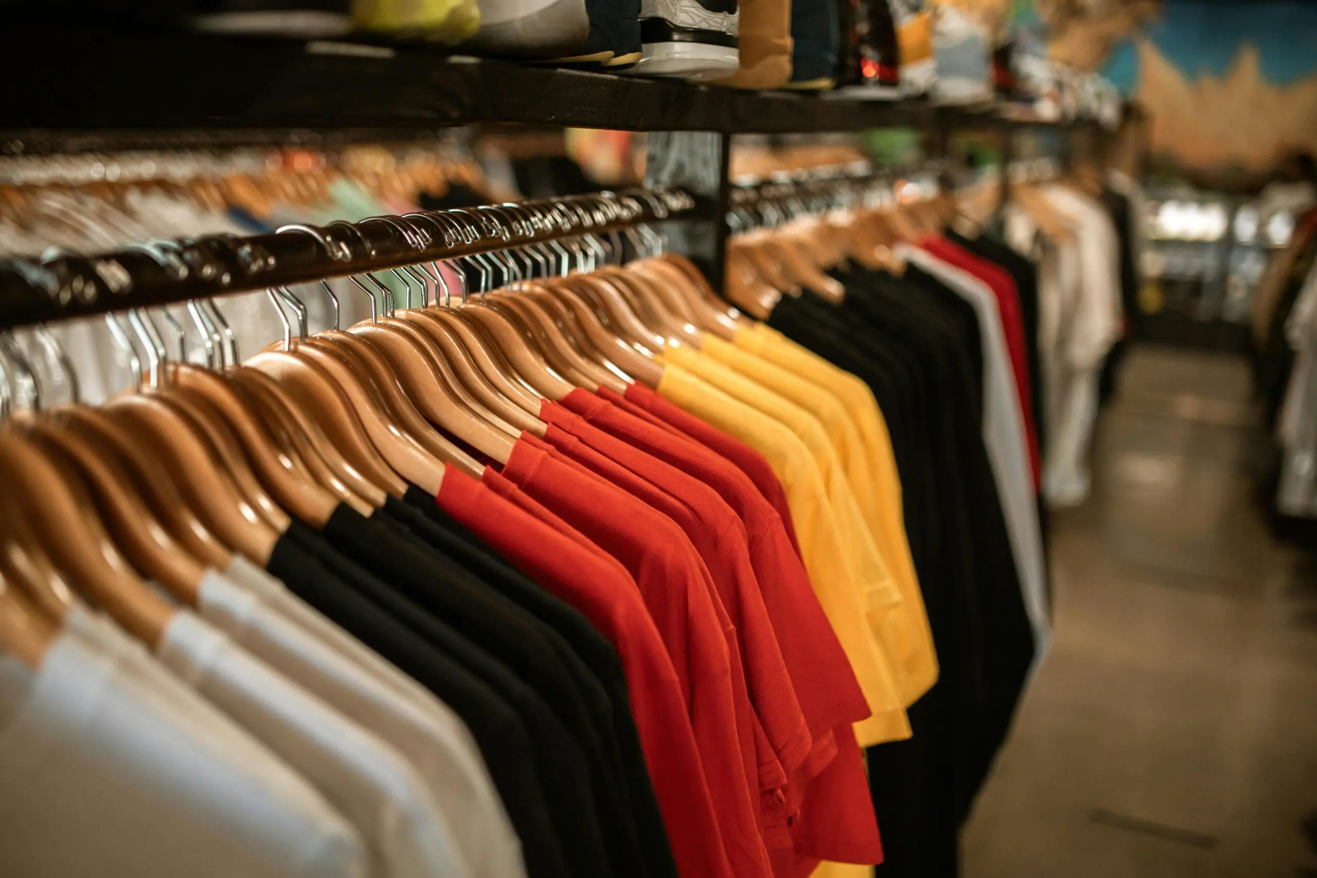 Racks of T-shirts in assorted colors on wooden hangers